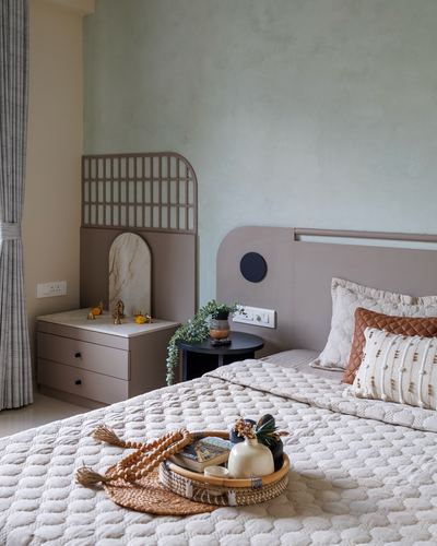Bedroom with mauve arched headboard, textured cream bedding, and lattice-screened dressing table