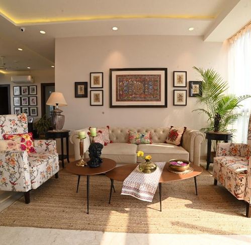 Living room with floral armchairs, tufted sofa, framed art wall, and nested round coffee tables on a jute rug