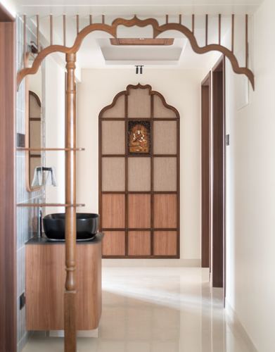 Carved wooden arch framing a hallway leading to a paneled wall with a small deity relief