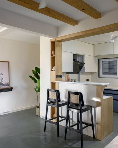 Kitchen pass-through framed in wood with cane bar stools and exposed ceiling beams