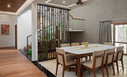 Open dining area beside a slatted wood screen revealing a planted stairwell courtyard