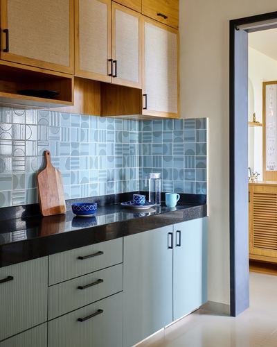 Kitchen corner with blue geometric tile backsplash, dark countertop and wood-cane upper cabinets