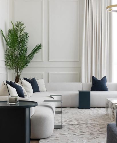Neutral living room with panelled walls, curved sectional sofa, navy accents, and a marble coffee table