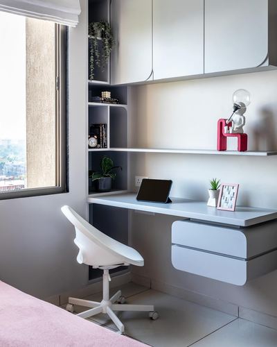 White floating study desk with wall shelving beside a window, white chair, tiled floor