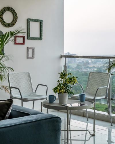Balcony seating with mesh chairs, round table, and mismatched frames on wall overlooking city view