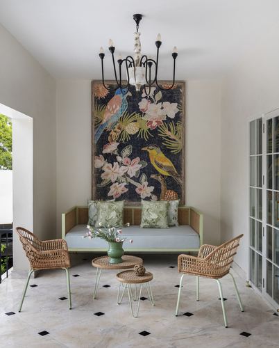 Sunroom with sage daybed, rattan chairs, bird tapestry and marble floor with black diamond inlay