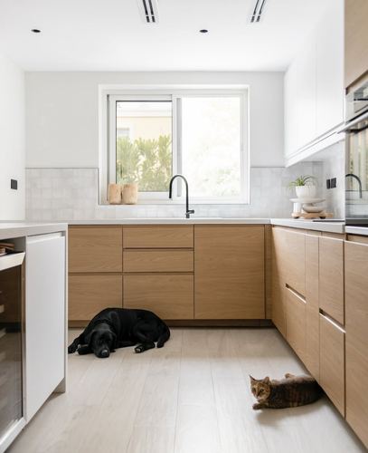 L-shaped kitchen with wood cabinetry, white counters, window over sink, dog and cat on floor