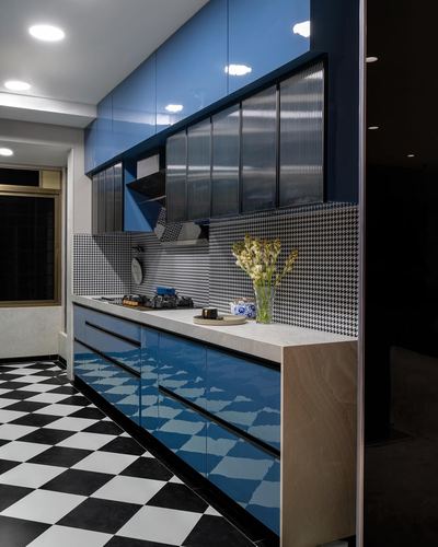 Glossy blue kitchen cabinetry with houndstooth backsplash and checkerboard floor