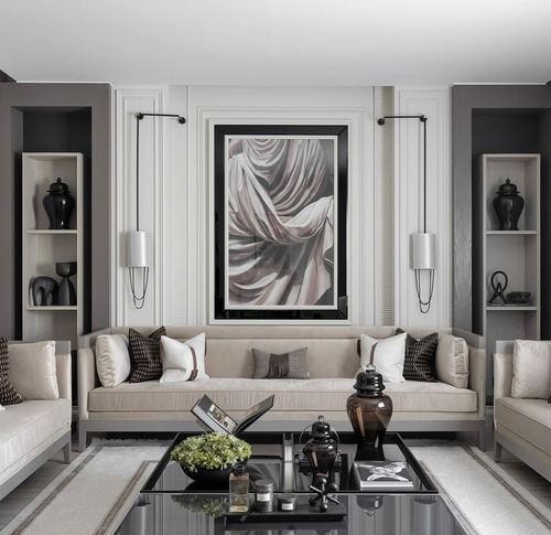 Symmetrical beige living room with black-framed drapery artwork, matching sofas, and dark coffee table