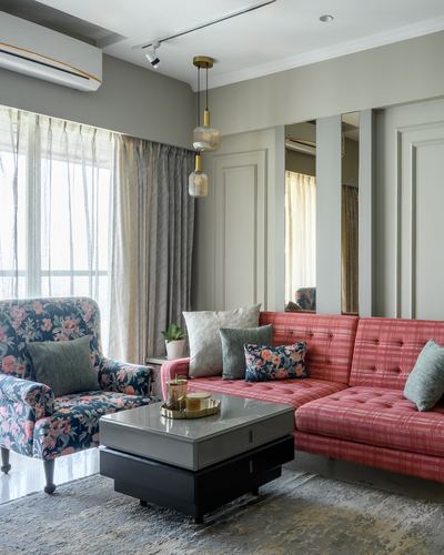 Living room with pink tufted sectional, floral armchair, and mirrored paneled wall