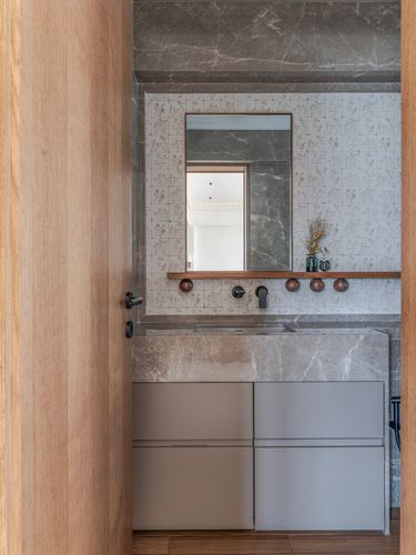 Doorway view into a powder room with stone counter, patterned tile wall, and mirror