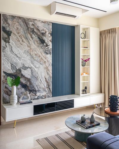 Living room with marble-look feature wall, blue fluted panel, white TV console and round coffee table