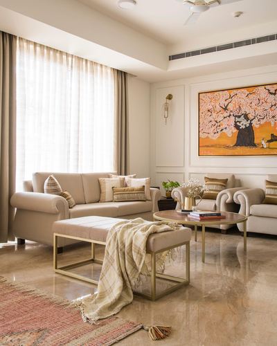 Beige living room with rolled-arm sofas, gold-framed bench, and orange tree painting
