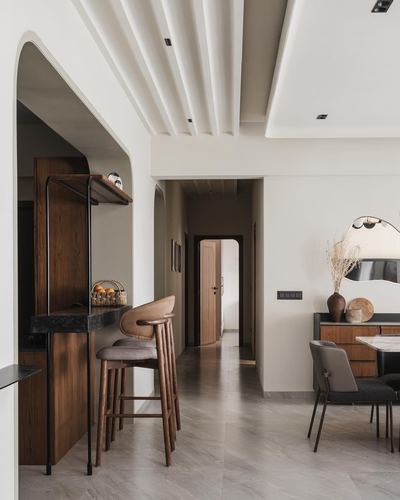 Arched wooden niche opens to a hallway and dining console in a minimalist Ahmedabad home