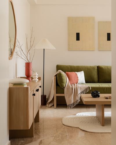 Japandi-style living room with wooden sideboard, olive sofa, and pleated floor lamp on stone floor