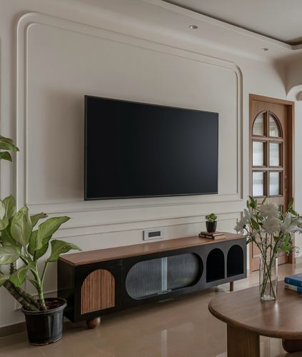 Living room with wall-mounted TV in arched moulded panel above a black wood console, arched door beside