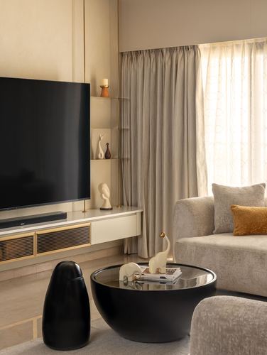 Living room with wall-mounted TV, floating console, sheer curtains, and round black coffee table.