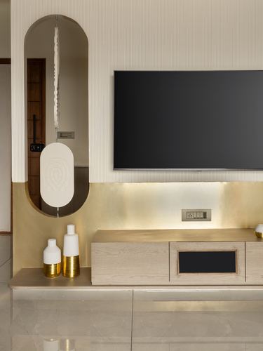 TV unit with brass backsplash beside an arched mirror niche in a neutral living room