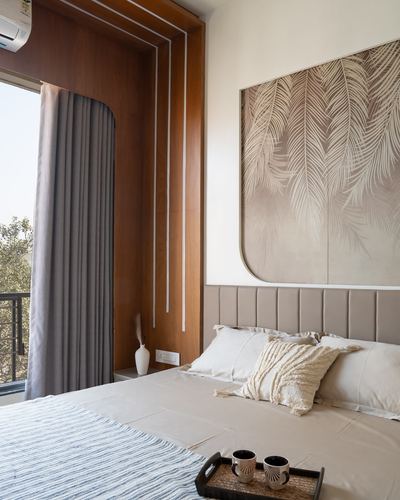 Bedroom with upholstered headboard, leaf-patterned wall panel, and arched wooden window recess