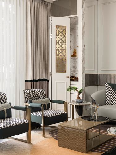 Living room with houndstooth chairs, gold coffee table, and a fretwork door opening to a small shrine niche