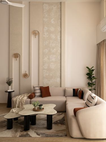 Beige living room with curved sectional sofa, arched wall niches, and carved central panel