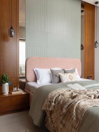 Bedroom with blush curved headboard, sage ribbed tile wall, wood panelling and hanging glass pendants