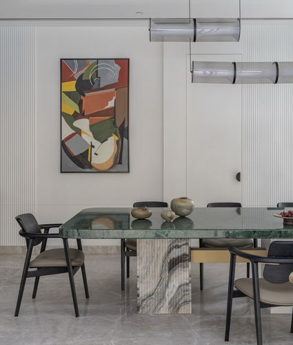 Dining room with green marble table, black chairs, abstract painting, tubular pendant lights