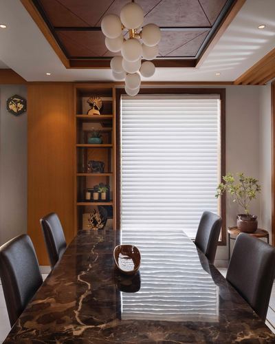 Dining room with marble table, leather chairs, wooden shelving and a sculptural bubble pendant light