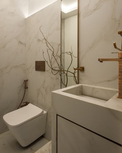 Marble powder room with floating stone sink, bronze fittings, wall-hung toilet and dried branch decor