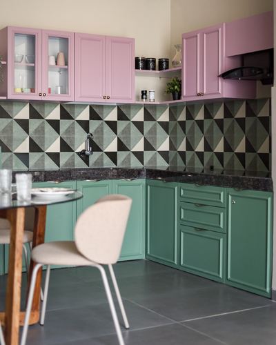 Corner kitchen with pink upper cabinets, green lower cabinets, and geometric tile backsplash