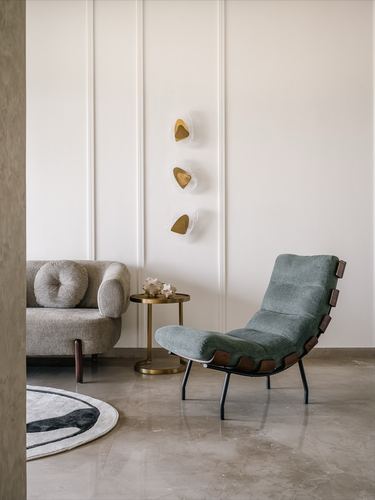 Living room corner with sage lounge chair, cane sofa, brass side table and three wall sconces