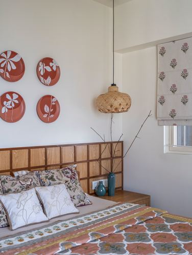 Bedroom with wood grid headboard, terracotta wall plates, and woven pendant light