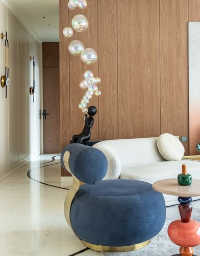 Living room with navy swivel chair, boucle sofa, wood-panelled wall, and bubble chandelier