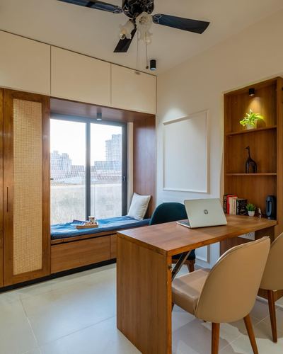 Home office with wooden desk, cane wardrobe, and window seat overlooking city view