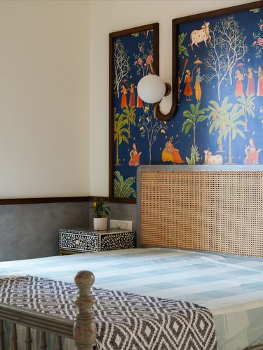 Bedroom with cane headboard, indigo pichwai-style mural panels, and inlay bedside table