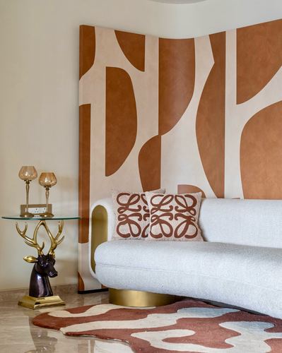 Curved cream boucle sofa against terracotta abstract mural with brass deer side table