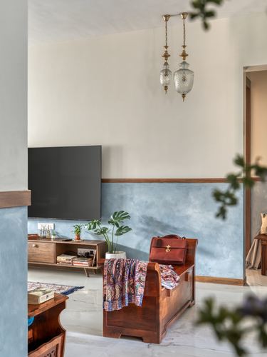 Living room with blue textured wainscot wall, wooden trunk bench, and hanging glass pendant lights