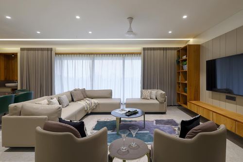 Beige sectional living room with round marble coffee table, wooden shelving and wall-mounted tv