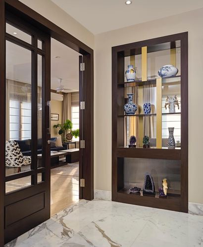 Foyer with glass-panelled dark wood door and mirrored display niche holding blue-white porcelain and geodes