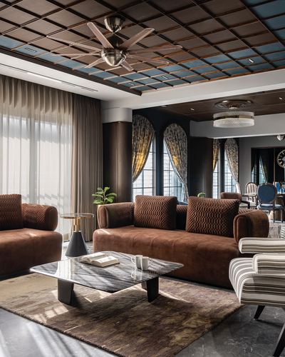 Luxurious living room with brown leather sofas, arched windows, and a patterned coffered ceiling