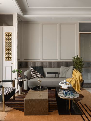 Living room with grey sofa, fluted paneling, marble coffee tables, mustard throw and patterned rug