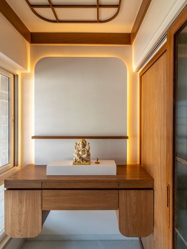 Arched pooja niche with backlit cove lighting and a brass Ganesha idol on a wooden console