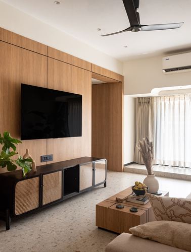 Living room with wood-panelled tv wall, cane-front console, terrazzo floor and curtained window