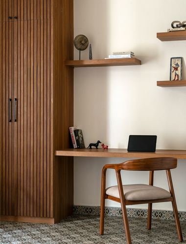 Wooden study nook with fluted wardrobe, floating shelves, desk, chair, and patterned tile floor
