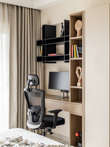 Bedroom study nook with wood desk, open shelving, monitor and black ergonomic chair