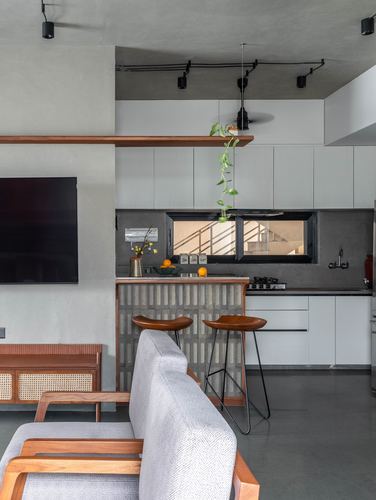 Open kitchen and living area with concrete ceiling, wood-topped bar counter and cane stools