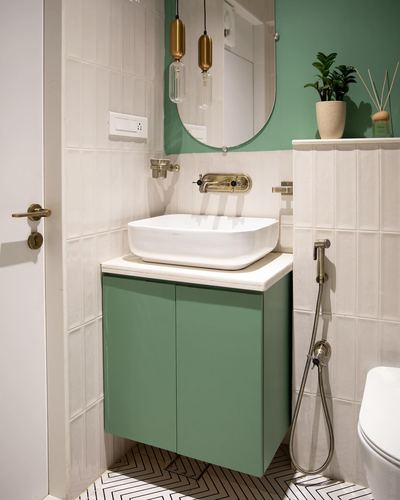 Bathroom vanity with green cabinet, white vessel sink, brass fittings, oval mirror and pendant lights.