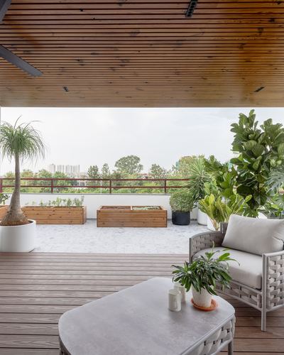 Rooftop terrace with wood-slat ceiling, wicker sofa, planter boxes and city view