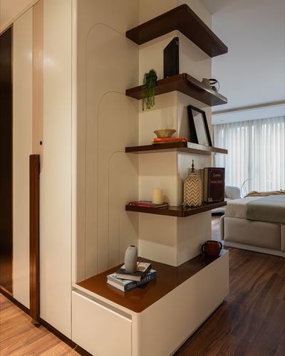Cream and walnut shelving unit dividing a passage from a bedroom with curated decor objects