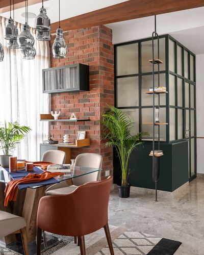 Dining area with brick column, glass table, and green-framed glass partition beyond